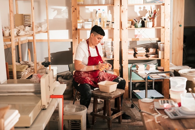 Joven alfarero limpiando las baldosas de cerámica en el taller.