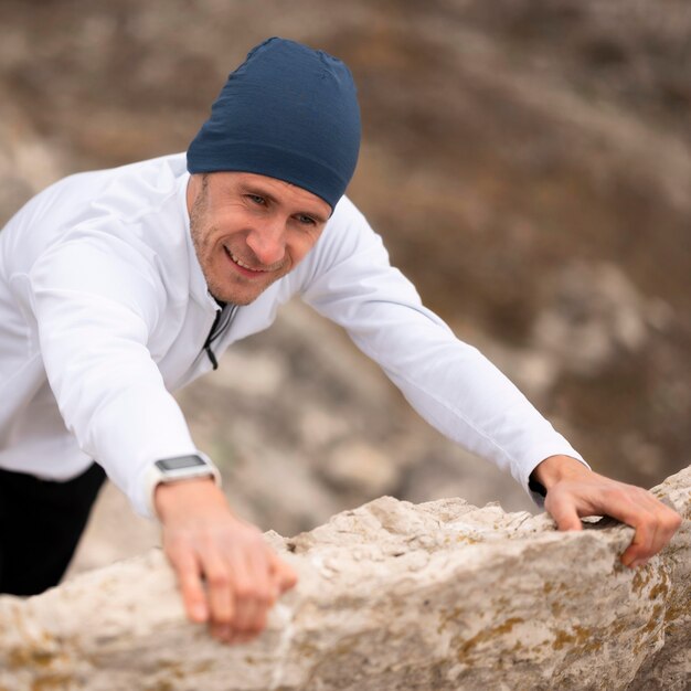 Joven de alto ángulo escalando rocas en la naturaleza