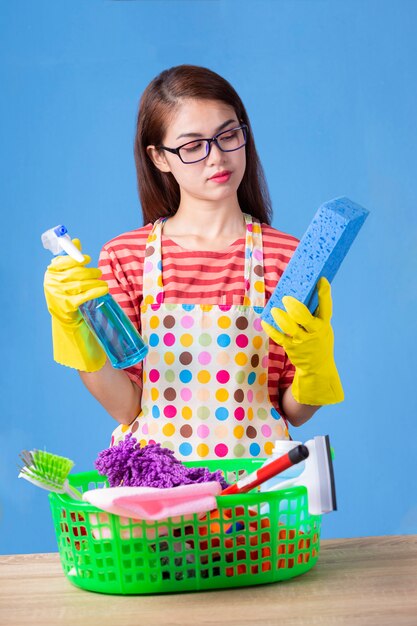 Joven ama de casa femenina con productos de limpieza