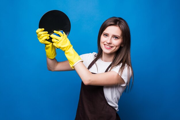 Joven ama de casa guantes de goma amarillos tiene una placa blanca y una esponja