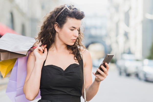 Joven amante de las compras usando teléfono celular