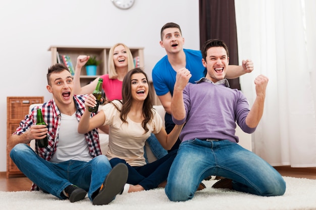 Joven amigo viendo la televisión y animando el fútbol