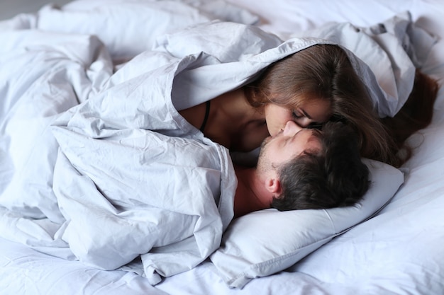 joven apasionada pareja besándose en la cama