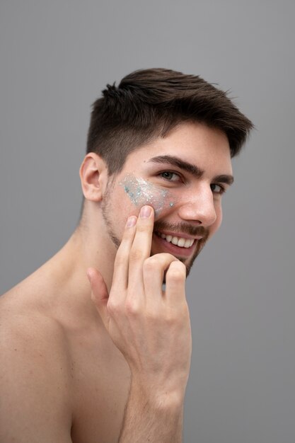 Joven aplicando loción brillante en su rostro