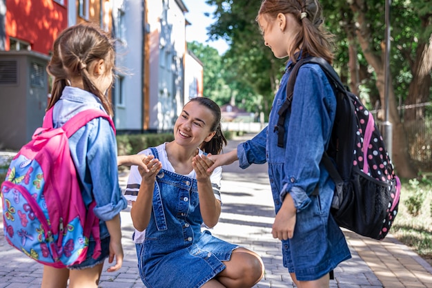 Una joven apoya moralmente a las hijas cogidas de la mano, anima a los niños, acompaña a los alumnos a la escuela.