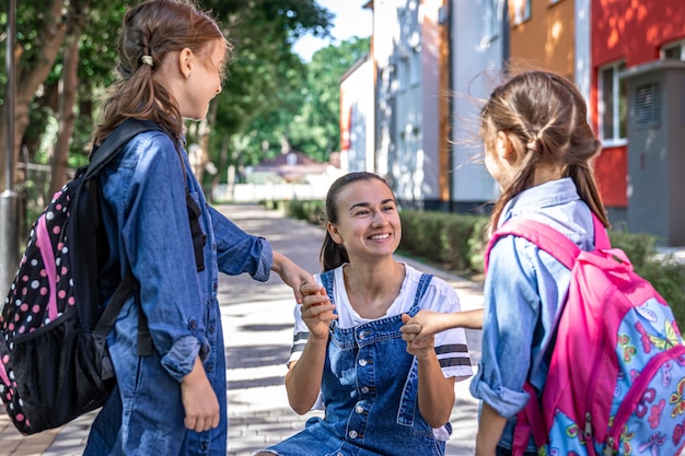 Foto gratuita una joven apoya moralmente a las hijas cogidas de la mano, anima a los niños, acompaña a los alumnos a la escuela.