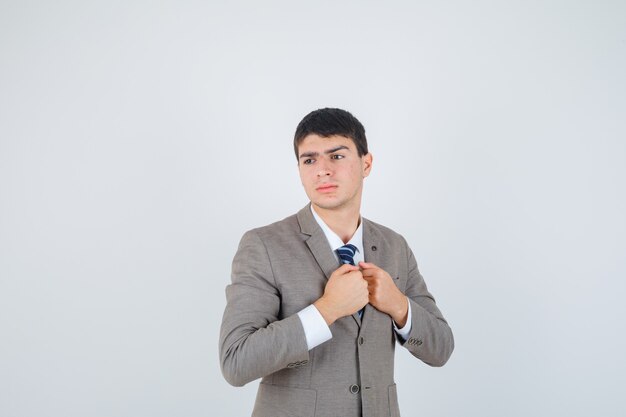 Joven apretando los puños sobre el pecho, mirando a otro lado en traje formal