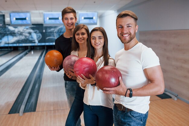 Joven apuesto. Amigos alegres se divierten en el club de bolos los fines de semana