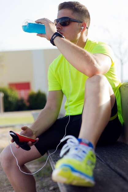 Joven apuesto beber después de correr.