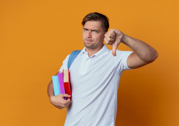 Joven apuesto estudiante insatisfecho con bolsa trasera sosteniendo libros