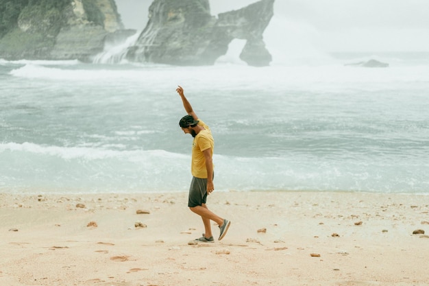 Joven apuesto hombre barbudo viajero junto al océano. playa de atuh, isla de nusa penida, indonesia. concepto de viaje. indonesia