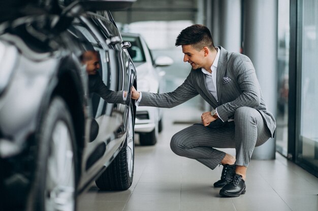 Joven apuesto hombre de negocios elegir un automóvil en una sala de exposición de automóviles