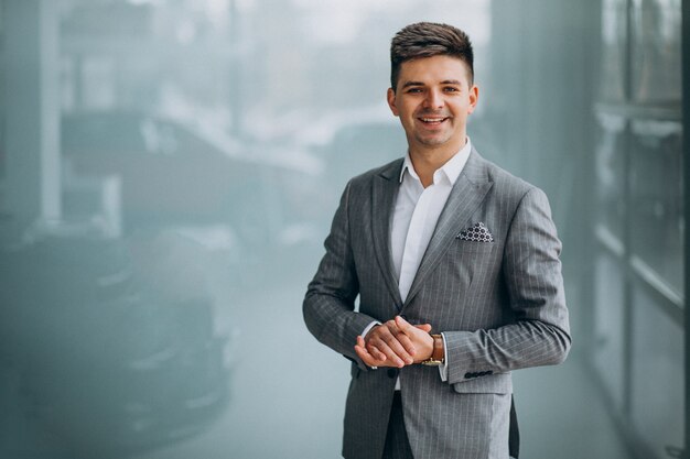 Joven apuesto hombre de negocios elegir un automóvil en una sala de exposición de automóviles