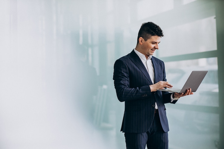 Foto gratuito joven apuesto hombre de negocios con ordenador portátil en la oficina