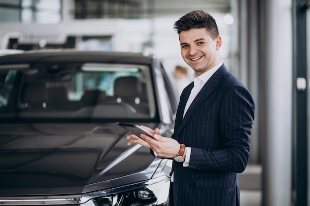 Joven apuesto hombre de negocios en un showrrom de coches