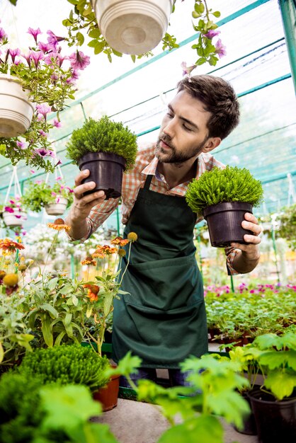 Joven apuesto jardinero alegre sonriendo, cuidando las flores