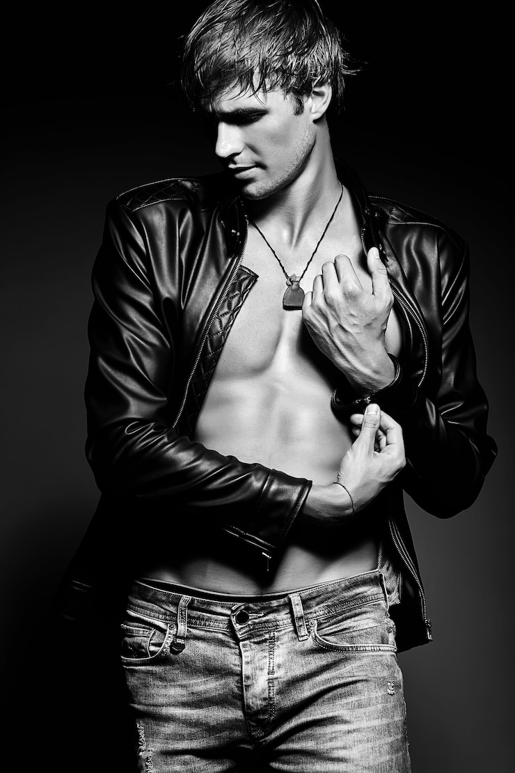 Foto gratuito joven apuesto musculoso hombre modelo masculino posando en el estudio mostrando sus músculos abdominales en la chaqueta de cuero