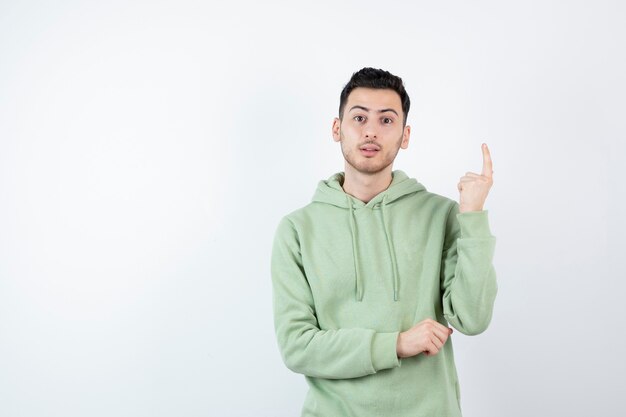 joven apuesto en sudadera con capucha de pie y posando.