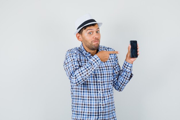 Joven apuntando al teléfono móvil en camisa a cuadros