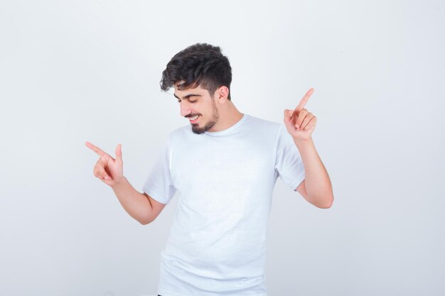 Joven apuntando a ambos lados en camiseta y mirando feliz