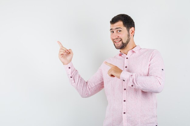 Joven apuntando con camisa rosa y mirando alegre