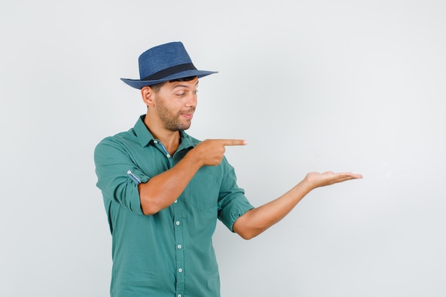 Joven apuntando a la palma de la mano a un lado en camisa