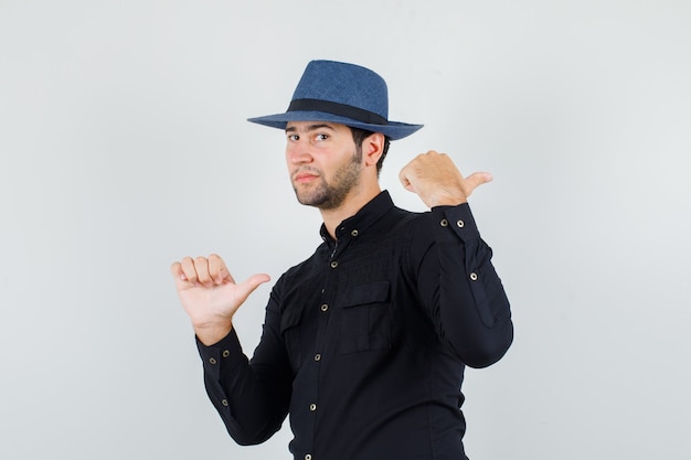 Joven apuntando los pulgares hacia atrás en camisa negra