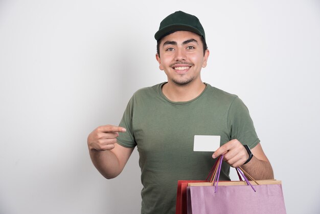 Joven apuntando a la tarjeta de crédito sobre fondo blanco.