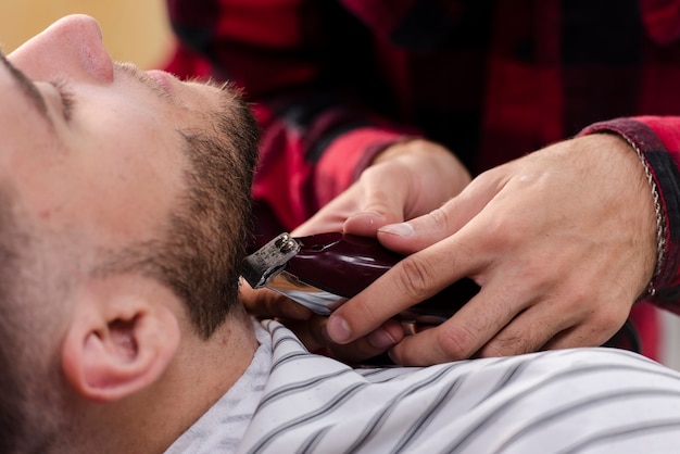 Joven arreglando su barba con una máquina de afeitar