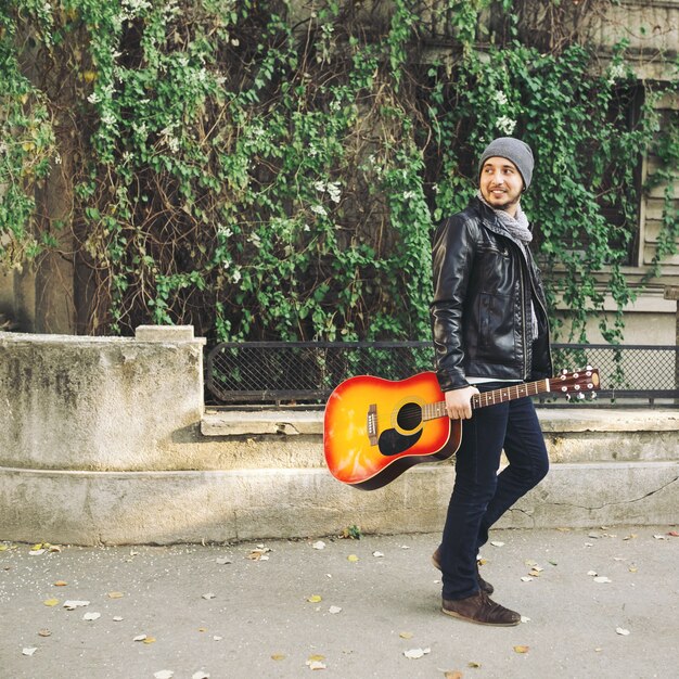 Joven artista callejero atractivo con su guitarra