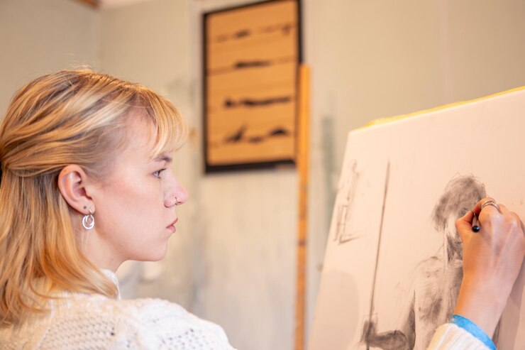 Foto gratuito una joven artista pinta en caballete en el estudio concepto de arte una mujer dibuja