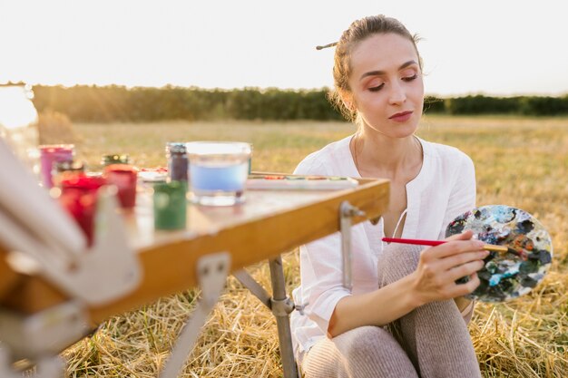 Joven artista pintando a mano en la naturaleza