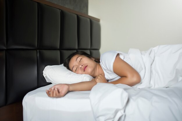 Joven asiática durmiendo en la cama