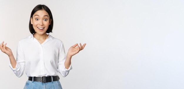 Una joven asiática emocionada que se ve feliz con incredulidad escucha noticias sorprendentes, información asombrosa sobre fondo blanco