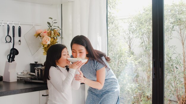 Joven asiática japonesa mamá e hija cocinando en casa. Mujeres de estilo de vida felices haciendo pasta y espagueti juntos para el desayuno en la cocina moderna en la casa por la mañana.