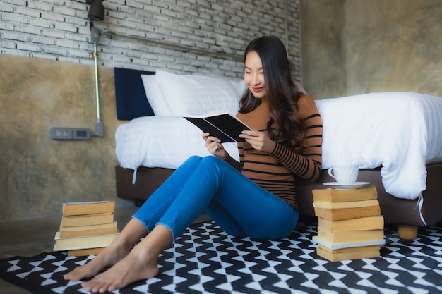 Joven asiática leyendo libros en el dormitorio