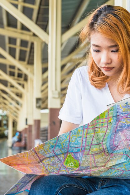 Joven asiática con mapa en plataforma