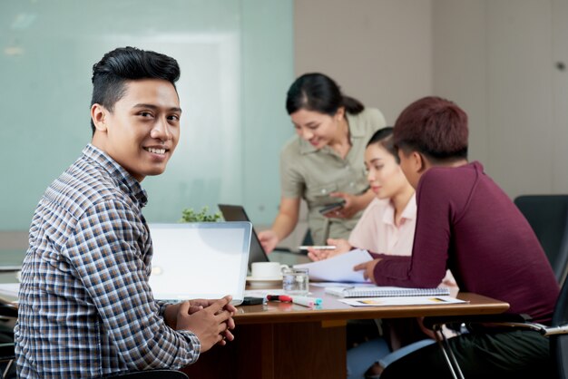 Joven asiática sentada en la mesa de reuniones en el trabajo