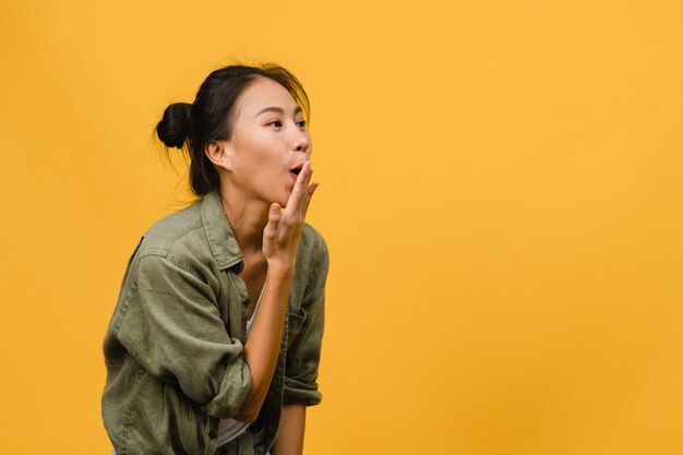 Joven asiática siente felicidad con expresión positiva, alegre sorpresa funky, vestida con un paño casual aislado en la pared amarilla. Feliz adorable mujer alegre se regocija con el éxito. Expresión facial.