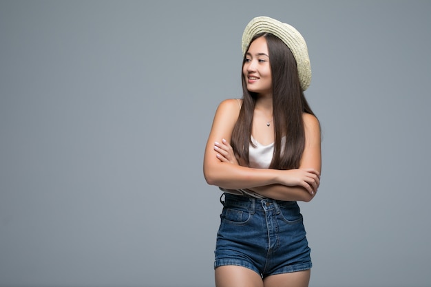 Joven asiática con sombrero de paja aislado sobre fondo gris
