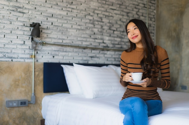 Joven asiática con taza de café en la cama