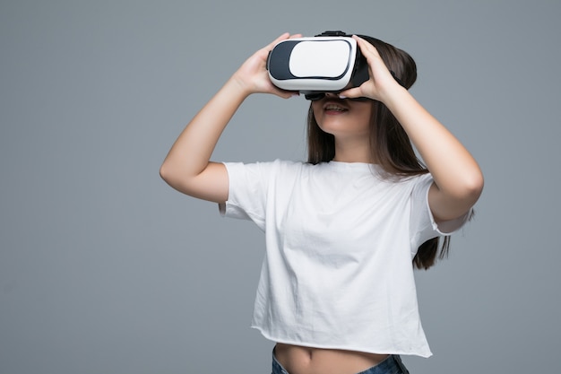 Joven asiática viendo VR sin embargo y toque la mano en el aire sobre fondo gris