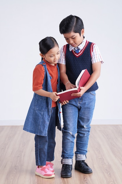 Foto gratuita joven asiático niño y niña de pie juntos y mirando el libro