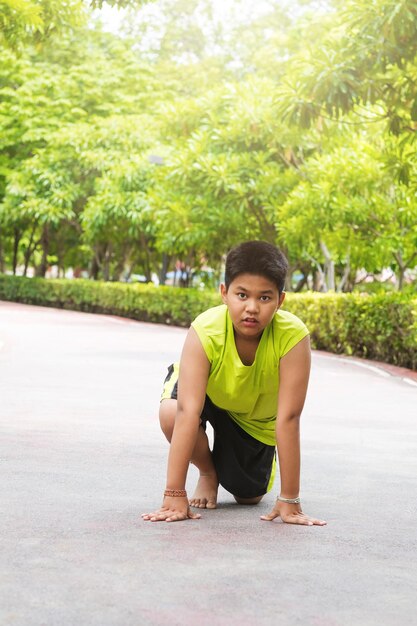 Un joven asiático se prepara para comenzar a correr en el jardín durante el día para practicar él mismo