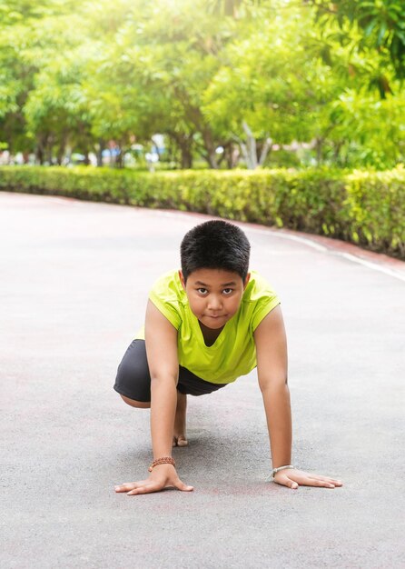 Foto gratuita un joven asiático se prepara para comenzar a correr en el jardín durante el día para practicar él mismo