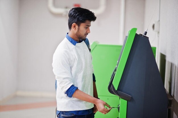 Joven asiático puso su tarjeta de crédito para sacar efectivo de un cajero automático verde