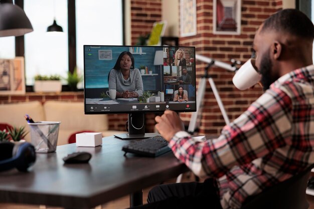 Joven asistiendo a una reunión de videollamada de negocios con personas, usando computadora y cámara web en casa. Trabajando de forma remota en una llamada de teleconferencia en línea, hablando en un chat de videoconferencia remota.