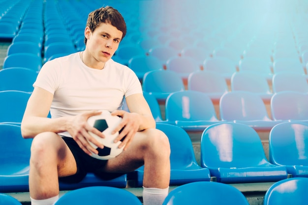 Joven atleta con balón de fútbol en el estadio