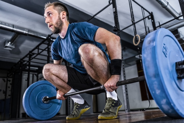 Un joven atleta haciendo levantamiento de pesas en un gimnasio.