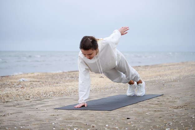 Joven atleta haciendo su ejercicio matutino en la playa Foto de alta calidad